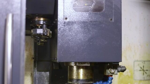 high precision CNC turning machine throwing coolant liquid on metal component in shaping forming process by vertical machining center control automation milling workpiece using rotating cutting tool
