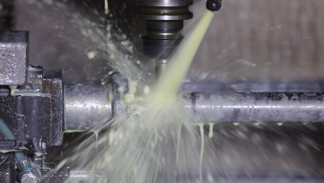 CNC machining high precision turning throwing coolant liquid on metal component in shaping forming process by vertical machining center control automation milling workpiece using rotating cutting tool