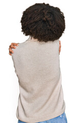 Young hispanic girl wearing wool winter sweater hugging oneself happy and positive from backwards....