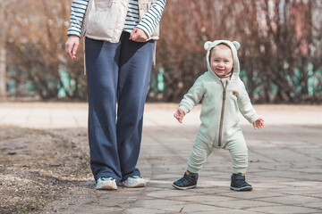 A handsome, cheerful little boy of two years old walks on the street in the spring. A kid in...