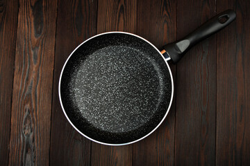 Metal frying pan: Ceramic coating with non-stick coating: Kitchen utensils; On a wooden background: Cooking for chefs in the kitchen.A place for the text.