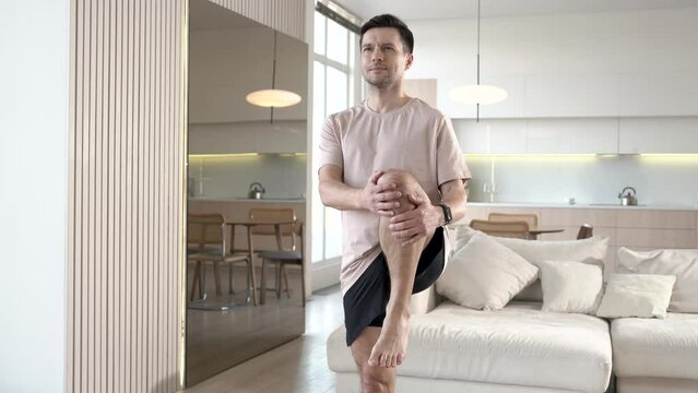 A man is doing warm-up body stretching exercises at home.
