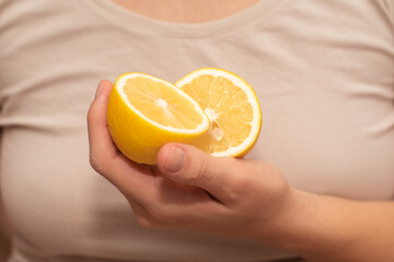 Hand Showcasing Half a Lemon. A person's fingers displaying a bright lemon half.