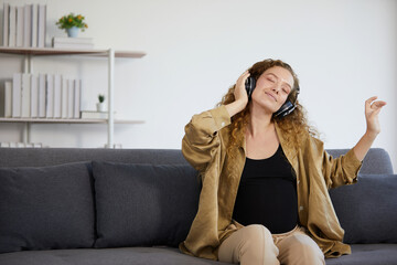 Obraz premium young woman with headphones and listening to music on sofa