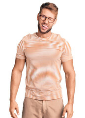 Young caucasian man wearing casual clothes and glasses winking looking at the camera with sexy...