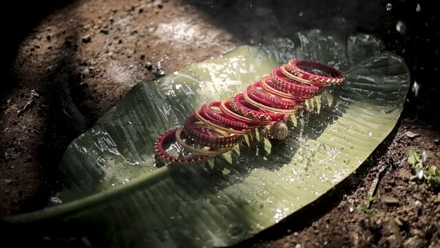 "Watch the mesmerizing video of a bride's bangles delicately resting on a leaf while water drops girth along them. This serene imagery captures the beauty of nature
