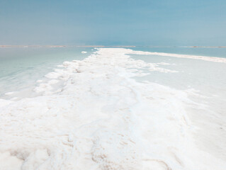 Landscape view on Dead Sea salt crystals formations, clear cyan green water at Ein Bokek beach,...