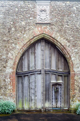 Beautiful old, big, vaulted wooden doors with a smaller door for people in an old wall.