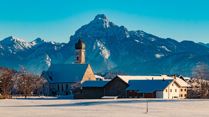 Church on a sunny winter day with the alps in the background near Eisenberg, Ostallgaeu, Bavaria, Germany