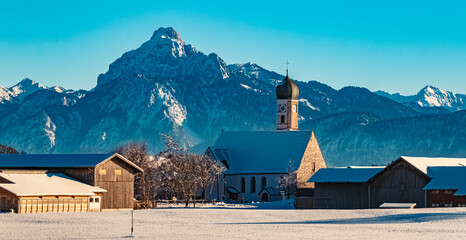 Church on a sunny winter day with the alps in the background near Eisenberg, Ostallgaeu, Bavaria, Germany