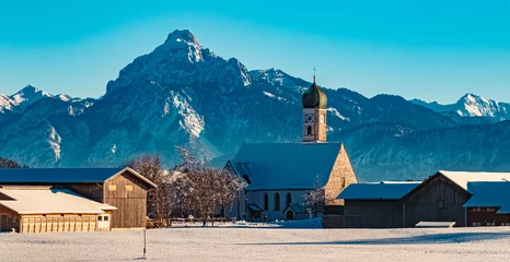 Photo sur Aluminium Alpes Church on a sunny winter day with the alps in the background near Eisenberg, Ostallgaeu, Bavaria, Germany