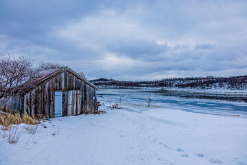 Fototapeta na wymiar Red cabin in a fjord in winter, Norway