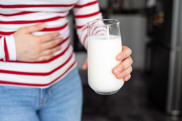 Lactose intolerance, health problem condition with dairy products. Woman holding a glass of milk has stomach ache.