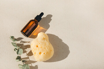 Set of natural cosmetics. Amber bottle with facial, bath liquid on a concrete background with natural bath sponge. Front view
