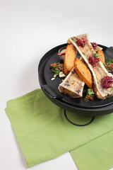 delicacy top view, baked bone marrow with croutons, herbs and spices on a black plate