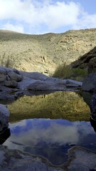 A pool of rainwater on the stream bed reflects the cloudy sky. Climate change concept