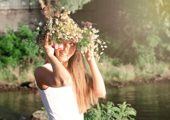 Cheerful cute happy woman in harmony and good mood with flowers on her head outdoors. Summer holidays and active pastime in nature. The lifestyle of modern people.