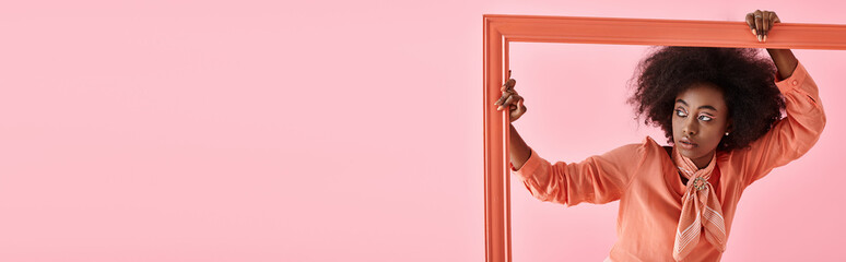banner, african american woman in peach fuzz blouse and neck scarf posing in frame on pink backdrop