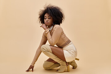 dreamy african american model in stylish outfit and thigh-high boots posing on beige background
