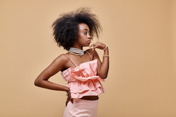 pretty african american girl in 20s posing in peach ruffle top and pastel skirt with hand on hip
