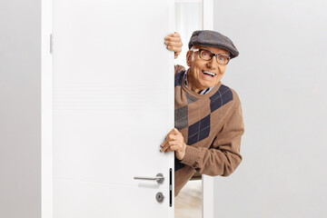 Elderly man standing behind a door