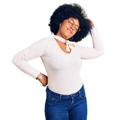 Young african american girl wearing casual clothes and glasses stretching back, tired and relaxed,...
