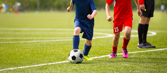 Two Soccer Players Running Along Sideline During League Match. Youth Football Players Compete in a Tournament