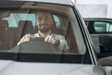 Man sitting in his new car in car showroom