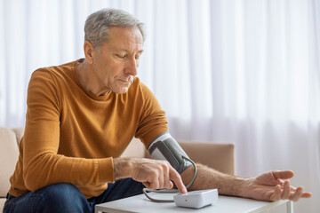Concerned senior checking blood pressure at home