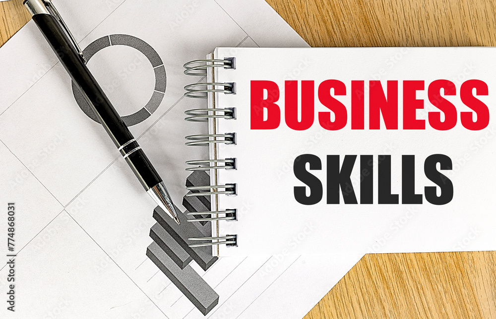 Aufkleber business skills text on notebook with chart on wooden background