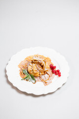 Top view of a delicious pancake with berries and mint leaves on a white plate