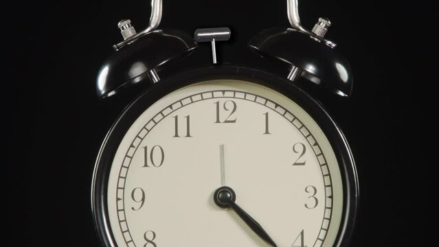 Alarm Clock Time. The hands of a classic alarm clock quickly rotate on the dial, stop abruptly at 12 and the bell mechanism is triggered
