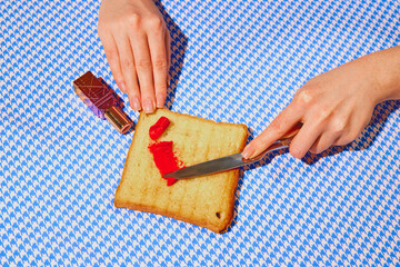 Promotional image of organic cosmetics products. Woman putting lipstick on toast bread against blue tablecloth. Concept of pop art photography, creativity, makeup, cosmetology