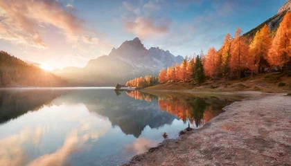 Poster first sunlight glowing hills of federa lake spectacular sunrise in dolomite alps with orange larch trees on the shore colorful morning scene of italy europe beauty of nature concept background © Claudio