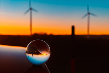 Crystal ball sunset with wind power plant silhouettes and reflections on a car roof near Kugl, Dingolfing-Landau, Bavaria, Germany