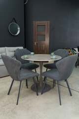 Gray wooden table combined with dark gray wooden chairs with soft fabric upholstery. There are blue porcelain mugs and saucers on the table