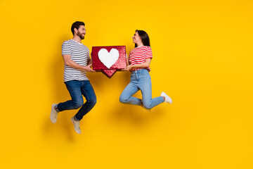 Fototapeta na wymiar Full length photo of funny couple wear striped t-shirt hold big social media like in palms isolated on vivid yellow color background