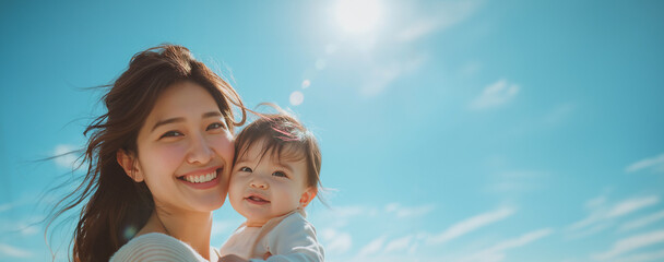 Portrait of joyful mother holds her smiling baby close, both basking in the sunlight under a clear blue sky, sharing a beautiful bonding moment. Love family Mother's Day concept
