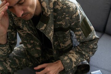 Depressed soldier with bottle sitting in living room. Alcohol addiction.