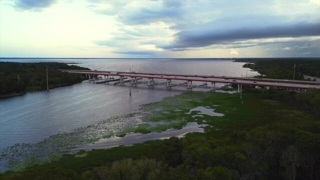 Drone of Lake Monroe and I4 Bridge with vehicles at sunset with cloudy sky in Sanford, Florida