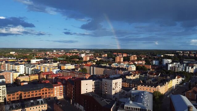 Drone view of blue cloudy sky with Rainbow over the buildings in Norrkoping City in Sweden