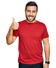 Young hispanic man wearing casual clothes smiling happy and positive, thumb up doing excellent and...