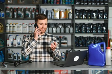 A salesman in an auto parts store is talking to a customer on the phone