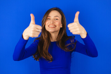 Optimistic brunette hair woman makes thumbs up gives approval shows excellent gesture says nice job...