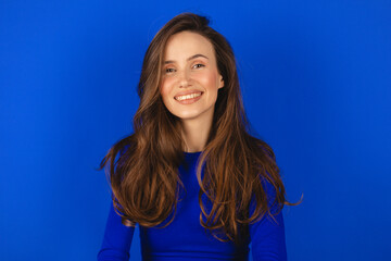 Happy cheerful young woman wearing blue long sleeves top rejoicing at positive news or birthday...