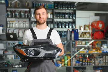 man holds automotive headlight in auto parts store - obrazy, fototapety, plakaty