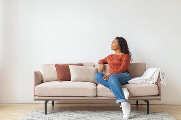 Fototapeta premium Black Woman Sitting on Couch in Living Room