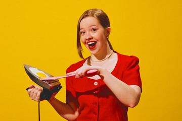 Smiling young woman in red dress cooking egg on iron, laughing against yellow background. Creative poster for cooking school and culinary workshop. Concept of pop art photography, creativity