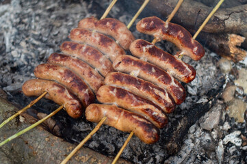Grilled sausages on the coals of a campfire