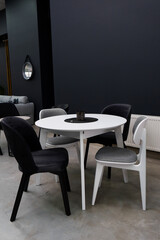 White wooden table combined with black and white wooden chairs with soft fabric upholstery. There is a black wax candle on the table